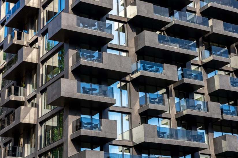 Close-up of a modern building facade with concrete balconies and blue glass, creating rhythm, symmetry, and urban aesthetics.